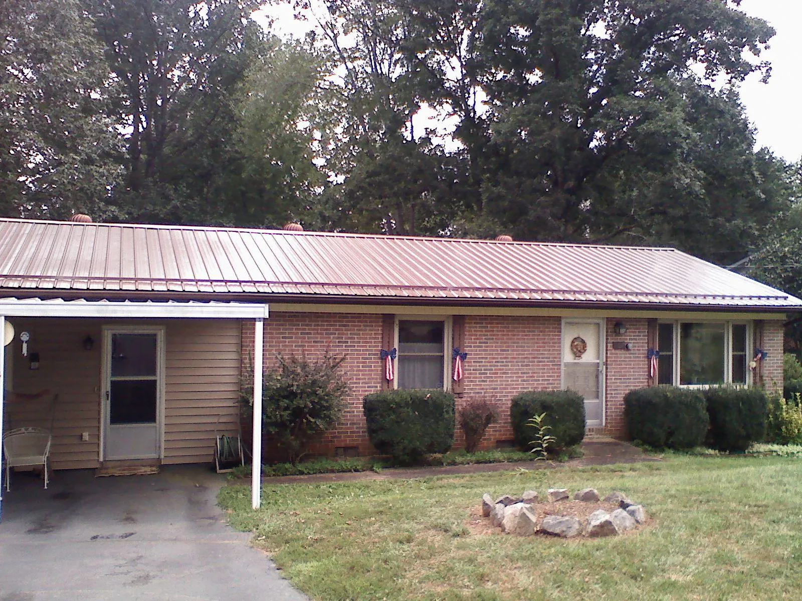 Bronze metal roof and carport on a brick ranch home — Roof Repair work by our crew in Masonville